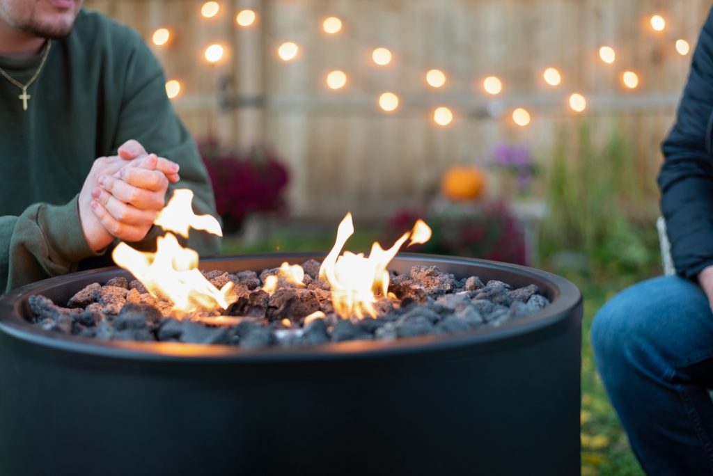 men sitting around a modern fire pit with outdoor lighting